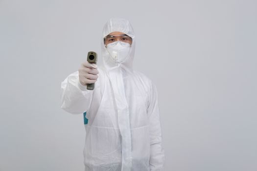 doctor man wearing biological protective uniform suit clothing, mask, gloves measuring body temperature with infrared forehead thermometer gun