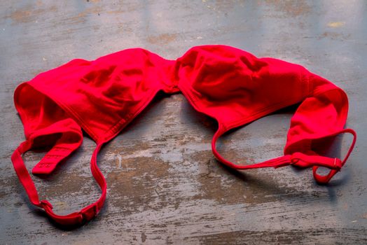 Red bra on rustic metallic floor. Romantic passion female lingerie. Sexy fashion background. Still life.