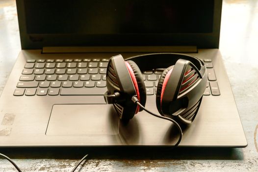 Portable over-ear Binaural Sound USB Headset with Microphone Noise Cancelling and Ultrasonic Volume Adjuster Headphone for Computer, Skype placed on laptop on morning sunlight. Music Background.