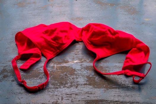 Red bra on rustic metallic floor. Romantic passion female lingerie. Sexy fashion background. Still life.