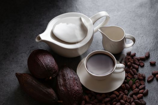 Hot chocolate and Cocoa pod cut exposing cocoa seeds on dark table, top view with copy space.