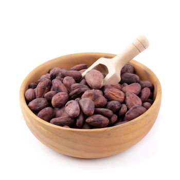 Cocoa fruit in a wooden bowl, raw cacao beans isolated on a white background.