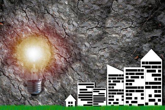 Ecology concept, save energy, paper city and light bulb on arid soil background
