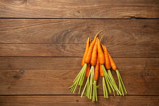 Fresh baby carrots on wooden cutting board and wooden background.