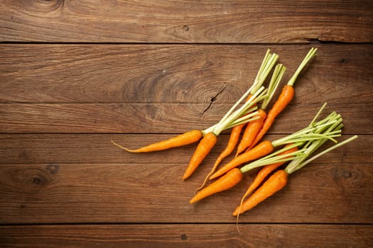 Fresh baby carrots on wooden cutting board and wooden background.