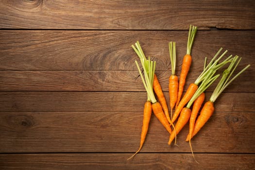 Fresh baby carrots on wooden cutting board and wooden background.