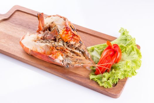 grilled giant river prawn with yellow creamy fat on head on a wooden plate.