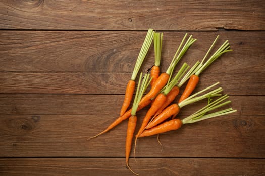 Fresh baby carrots on wooden cutting board and wooden background.