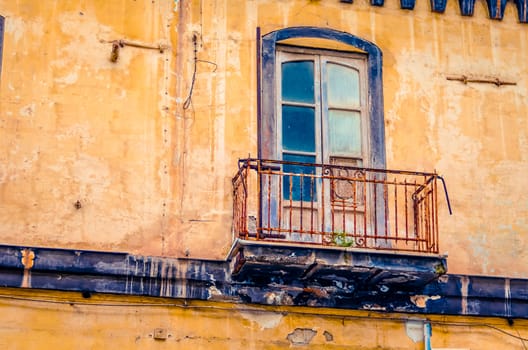 vintage balcony on an old abandoned and decaying house facade in Italy