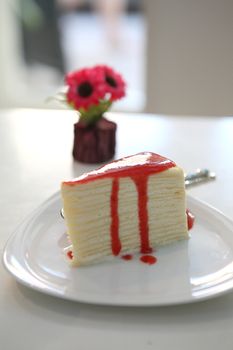 Crape cake pour with strawberry sauce on plate 