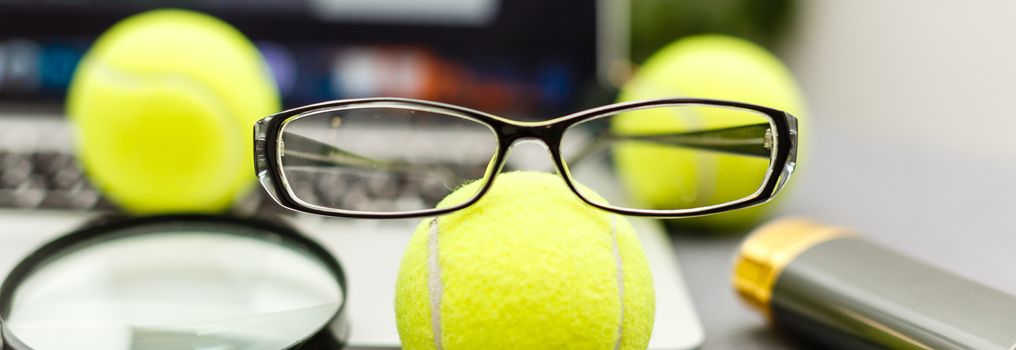 Top view of laptop, Sports Equipment, Tennis ball, glasses on the Sports administration white table.Business concept.