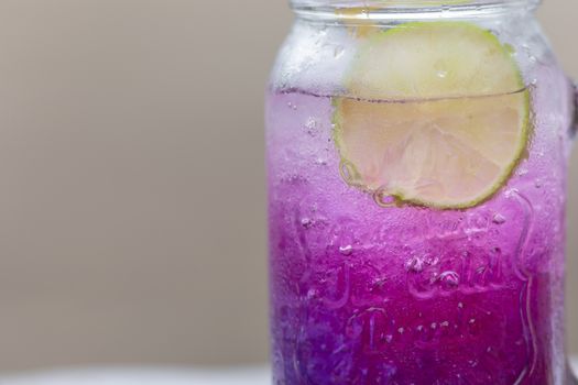 Fresh purple Butterfly pea or blue pea flower and lemon juice in glass with green blur background.