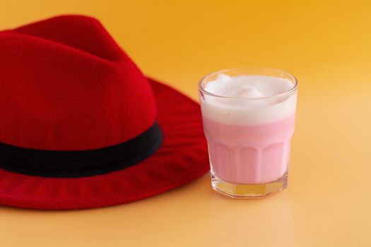 Red hat and Strawberry milk shake from the glass on yellow background.