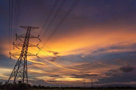 Colorful dramatic sky with Silhouette of high voltage pole and sunset.