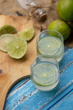 Lime juice and lemon on a blue wooden table.
