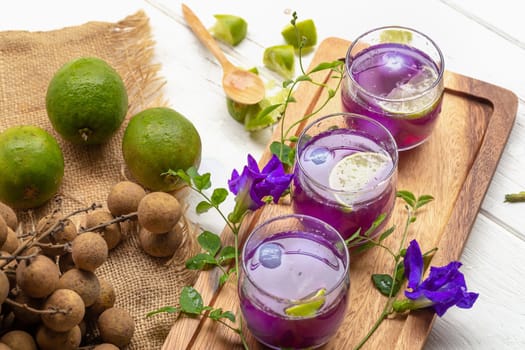 Glass of lemon juice, Pea flowers and Longan on white wooden table.