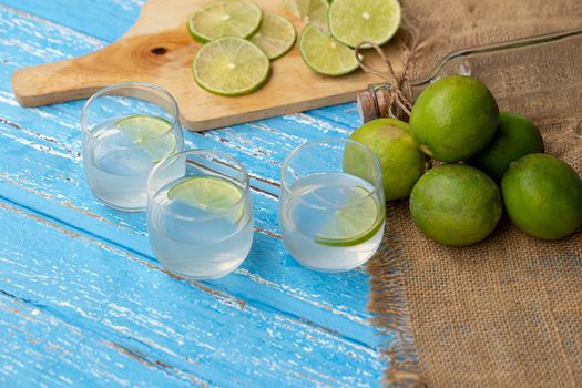 Lime juice and lemon on a blue wooden table.