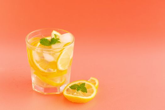 Detox Water with lemon in a glass on an orange background.