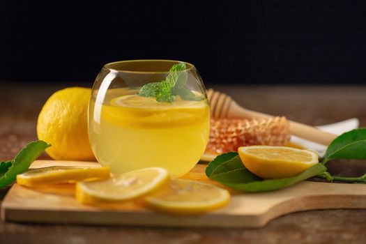 Lemon juice with honey on wooden table,  lemons and sage leaves.
