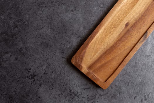 Wooden cutting board on black table background.