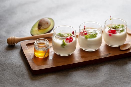 Glass of Cherry and avocado sliced in yogurt on wooden background.