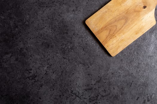 Wooden cutting board on black table background.