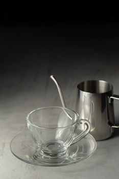 Glass of coffee and Stainless steel pitcher on the cement table.