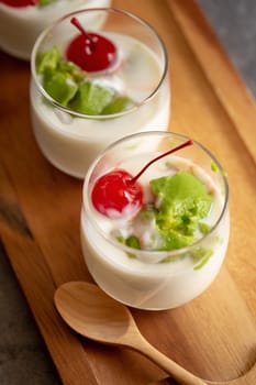 Glass of Cherry and avocado sliced in yogurt on wooden background.