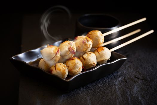 Roasted pork ball pour with sweet spicy sauce on dark background.