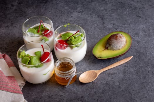 Glass of Cherry and avocado sliced in yogurt on wooden background.