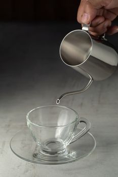 Glass of coffee and Stainless steel pitcher on the cement table.