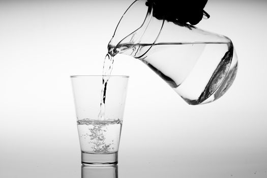 Glass of water with pouring from the bottle, studio shot