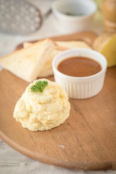 Mashed potatoes in a plate on a wooden table.