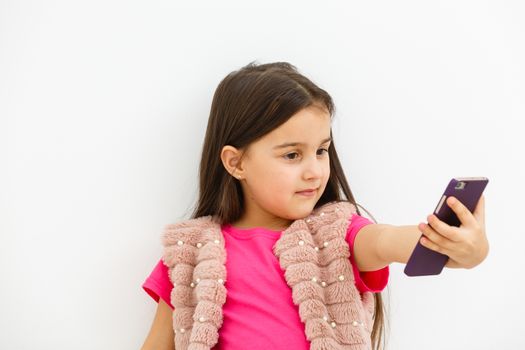 Portrait of little girl taking a selfie isolated over white background