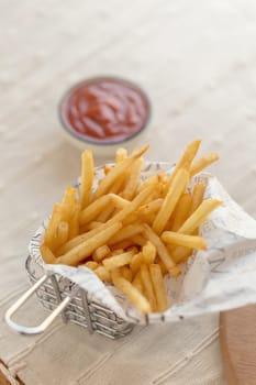 French fries with ketchup on wooden background.