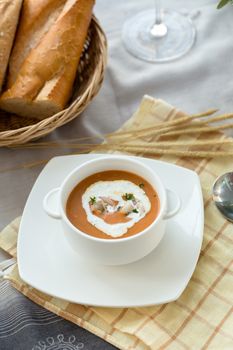 Vegetable cream soup with shrimps and croutons in white bowl close up.