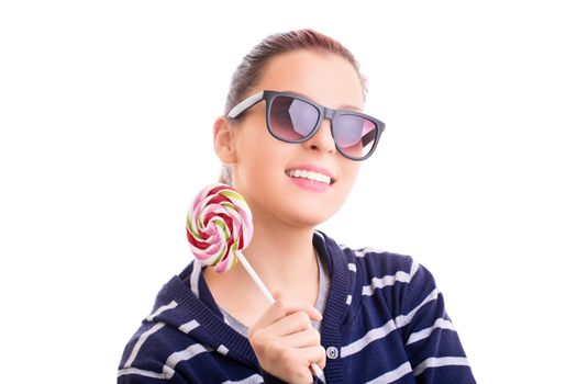 Beautiful young girl in casual clothes with sunglasses holding a colorful lollipop, isolated on white background.