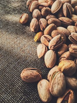 Pistachio nuts on rustic linen background, food and nutrition