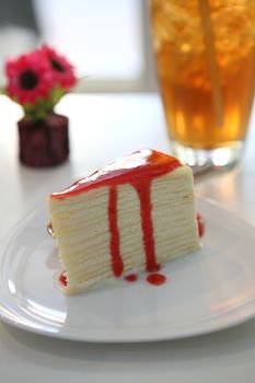 Crape cake pour with strawberry sauce on plate 