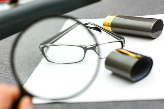 magnifier and glasses on a sheet of paper for business behind blind
