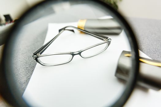 Business summary reports and a magnifying glass with glasses on table office. Concept of Data Analysis, Investment Planning, Business Analytics.