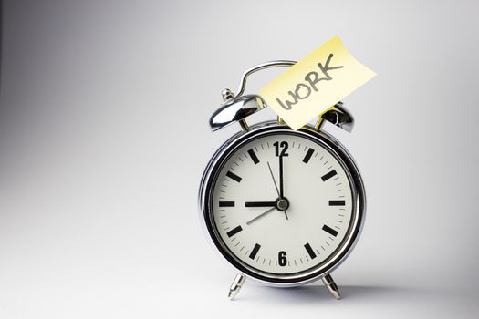 Alarm clock with sticky paper note on white background