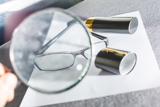 magnifier and glasses on a sheet of paper for business behind blind