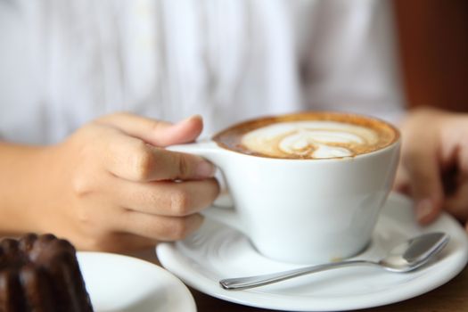 woman hands with cappuccino coffee on a wood table