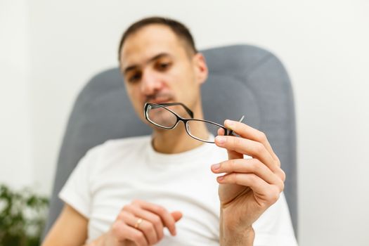 Young man puts his glasses on