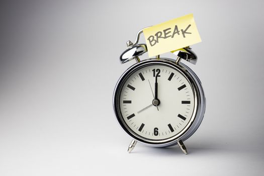 Alarm clock with sticky paper note on white background