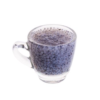 Glass of basil seeds in syrup on a white background.