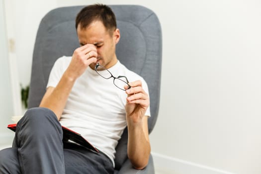 Man with tired eyes after long work holding his eyeglasses