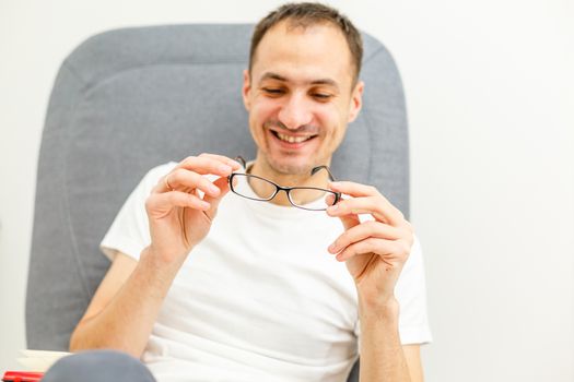 Young man puts his glasses on