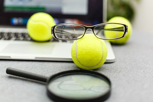 Top view of laptop, Sports Equipment, Tennis ball, glasses on the Sports administration white table.Business concept.